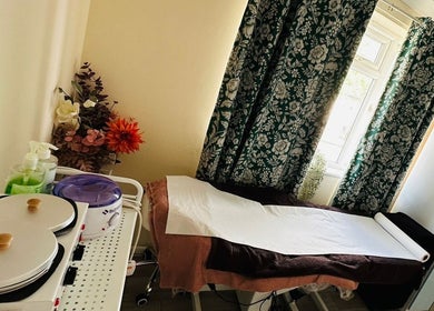 Nudeblush Studio waxing room in Stanwell, England with cozy decor and equipment by a sunlit window.
