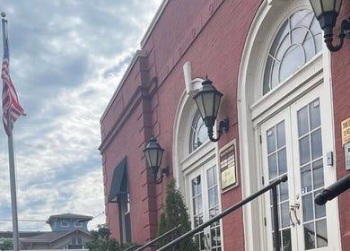 A classic brick facade of Deep Roots Hair Atelier in Riverhead, New York, US featuring elegant arched windows.