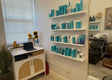 Bright salon corner at Deep Roots Hair Atelier, Riverhead, New York, with shelves of hair products and cozy decor.