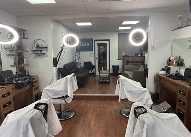 Modern interior of Dilla Barbershop Urmston, England, GB featuring stylish chairs and ambient lighting.