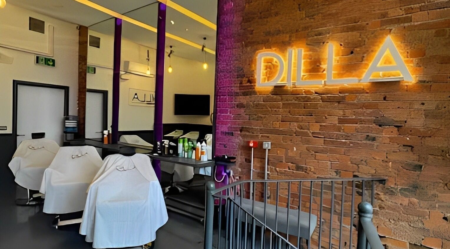 Interior view of Dilla Barbershop Manchester, featuring barber chairs and exposed brick walls in Manchester, England, GB.