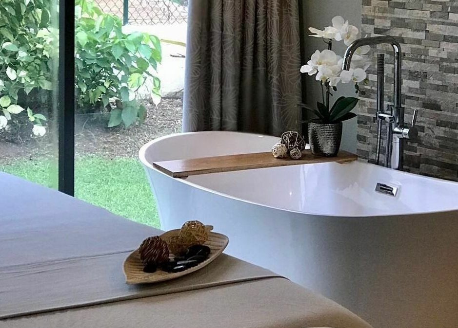 Luxurious spa bath and massage table at REFLECTIONS SPA BARBADOS, Bridgetown, Christ Church, BB, amid lush greenery.