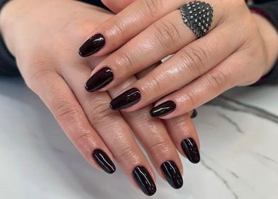 Chic black manicure at Tynaesthetics_ in London, England, GB, showcasing glossy nail art expertise.