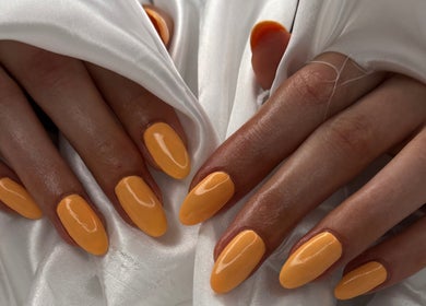 Elegant glossed golden nails on a white fabric backdrop at Tynaesthetics_, London, England, GB.