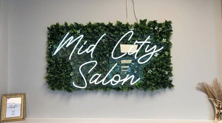 B. Hive Salon wall decor in Huntsville, Alabama, US with lush greenery and elegant sign.