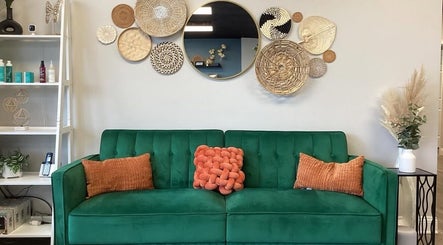 Stylish seating area with green sofa at B. Hive Salon, Huntsville, Alabama, US showcasing cozy decor.