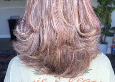 Stylish layered hairstyle at B. Hive Salon, Huntsville, Alabama, US, showcasing vibrant highlights and curls.