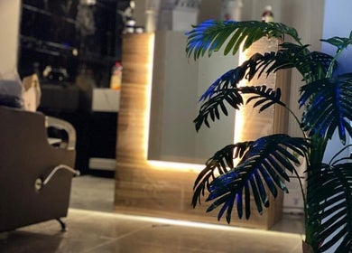 Elegant salon interior at Buzz Stop, Taif, Makkah Province, SA with illuminated mirror and lush plant.