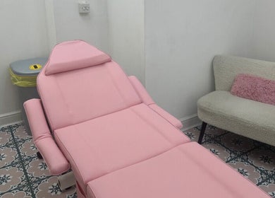 Cozy pink treatment room at Angel Aesthetics, Stourbridge, England, GB with a stylish chair and sofa.