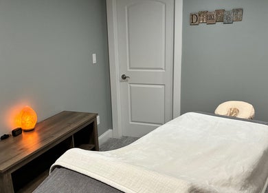 Peaceful massage room at It Is Well, Burlington, Wisconsin, US, featuring a cozy bed and soothing salt lamp.