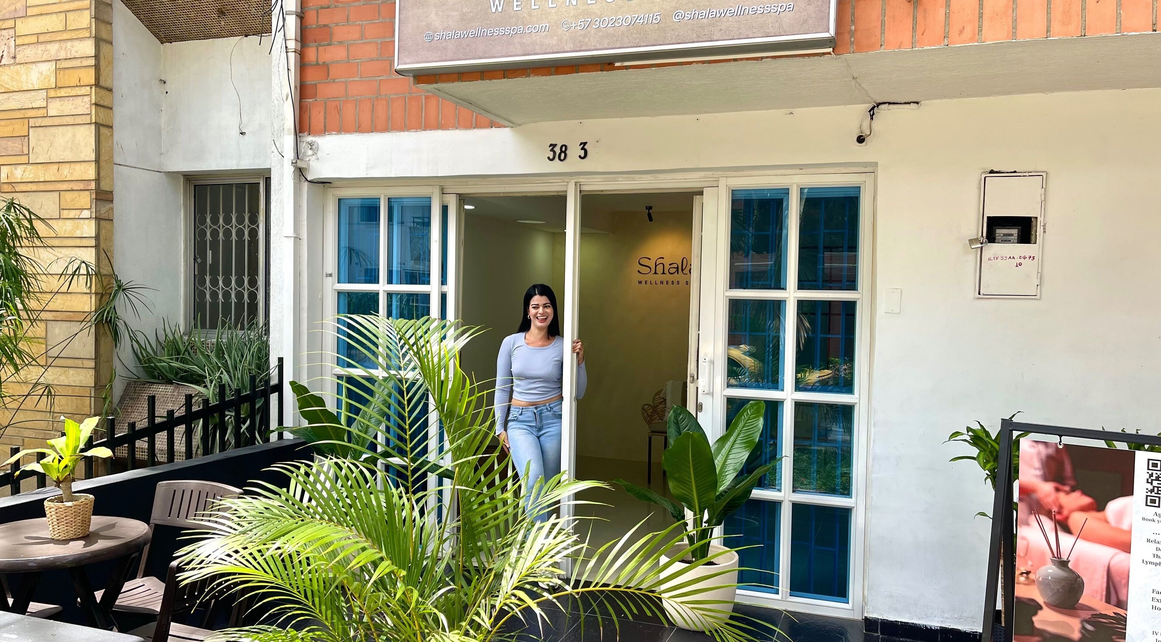 Entrada de Shalá Wellness Spa en Medellín, Antioquia, CO con puertas abiertas y plantas enmarcando la entrada.