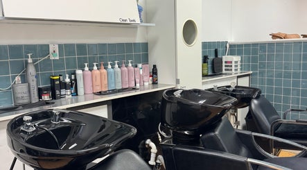 Sleek black shampoo chairs at Valeria’s Beauty Studio in Kennesaw, Georgia, US, with product bottles on shelves.