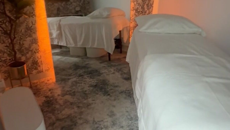 Calm massage room with two beds at Shalom Massage, Mcallen, Texas, US featuring warm lighting and floral decor.