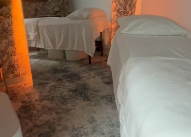 Calm massage room with two beds at Shalom Massage, Mcallen, Texas, US featuring warm lighting and floral decor.