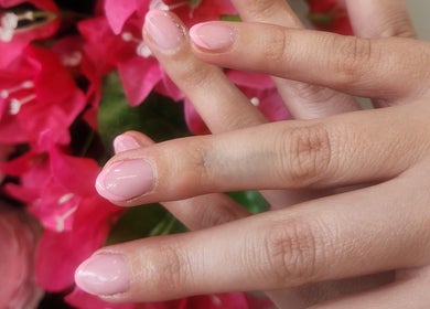 Elegant pink manicure at L'amitie in Flemington, New Jersey, US with vibrant flower backdrop.