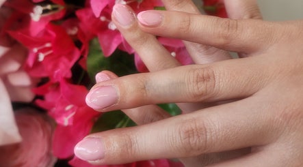 Elegant pink manicure at L'amitie in Flemington, New Jersey, US with vibrant flower backdrop.
