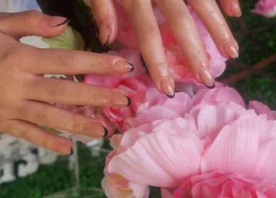 Elegant manicured hands with black-tipped nails by flowers at L'amitié, Flemington, New Jersey, US.
