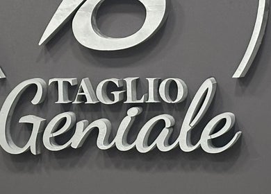 Insegna elegante di Taglio Geniale a Parenti, Calabria, IT. Scritta stilizzata su sfondo grigio.
