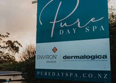 Pure Day Spa entrance sign amidst trees in Kerikeri, Northland, NZ, highlighting Environ and Dermalogica products.