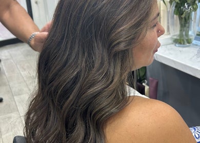 Client with wavy hair styled at The Royal Salon, London, England, GB, showcasing sleek and elegant beauty.