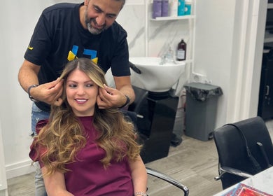 Hair stylist perfecting a woman's look at The Royal Salon, London, England, GB.