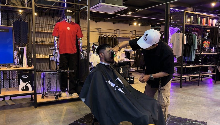 Barber at The Valet Barber, Ampang, Selangor, MY, skillfully trims customer's beard.