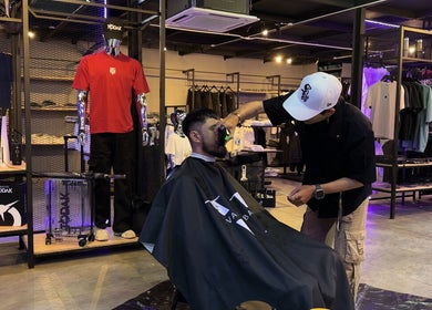 Barber at The Valet Barber, Ampang, Selangor, MY, skillfully trims customer's beard.