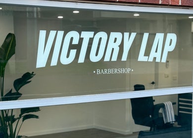 Front window of Victory Lap Barbershop in Melbourne, Victoria, AU showcasing the stylish interior.