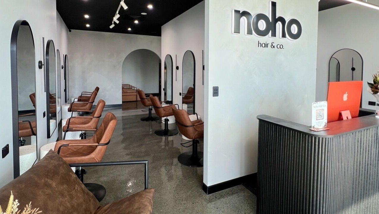 Modern interior of Noho Hair & Co. in Ormeau, Queensland, AU, featuring stylish salon chairs and a sleek reception desk.