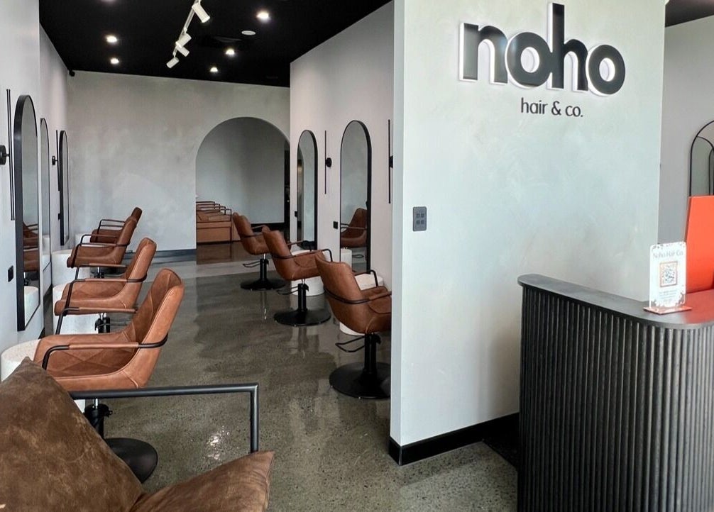 Modern interior of Noho Hair & Co. in Ormeau, Queensland, AU, featuring stylish salon chairs and a sleek reception desk.
