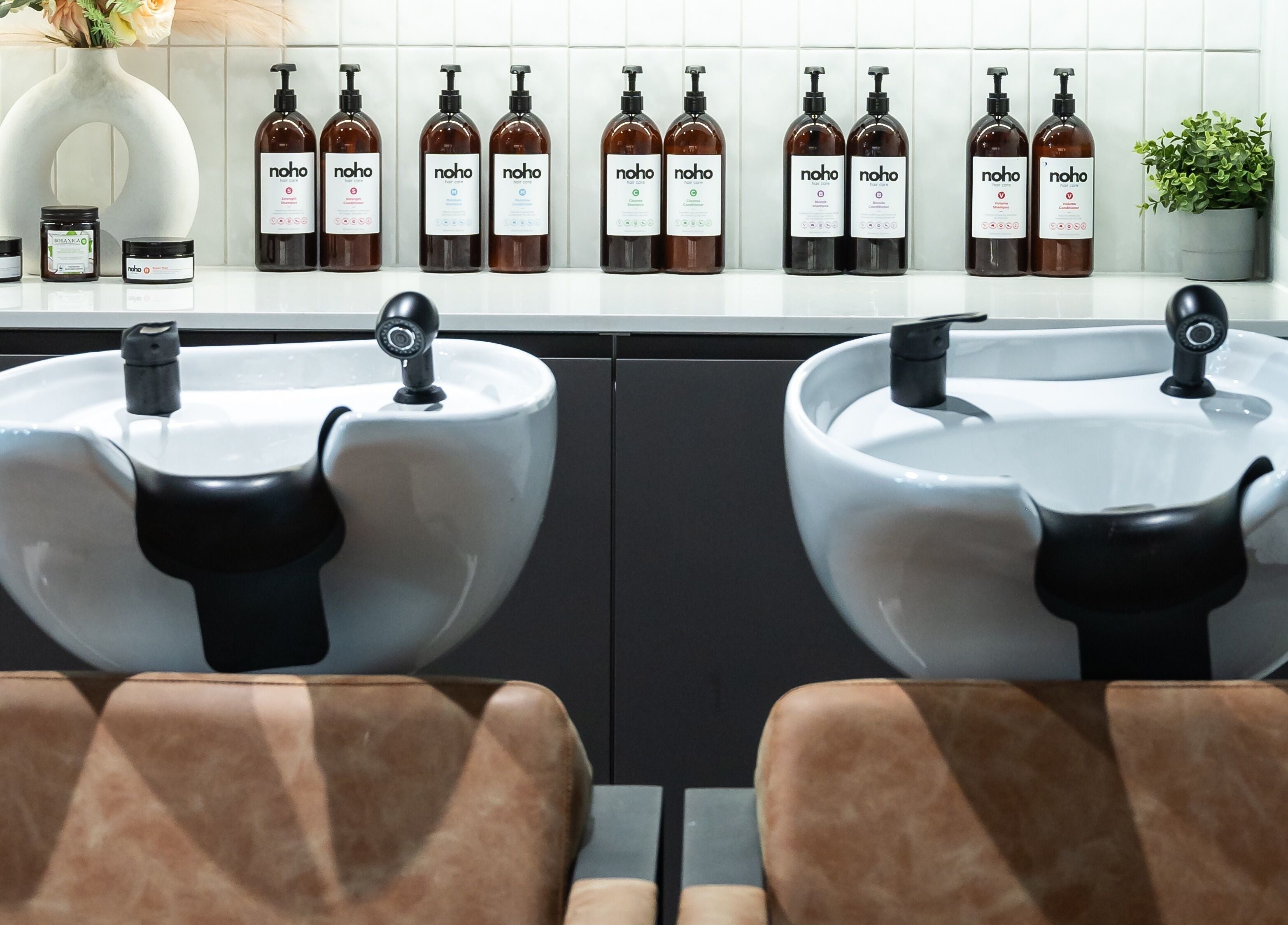 Luxurious wash stations at Noho Hair & Co., Ormeau, Queensland, AU, with stylish shampoo bottles and decor.