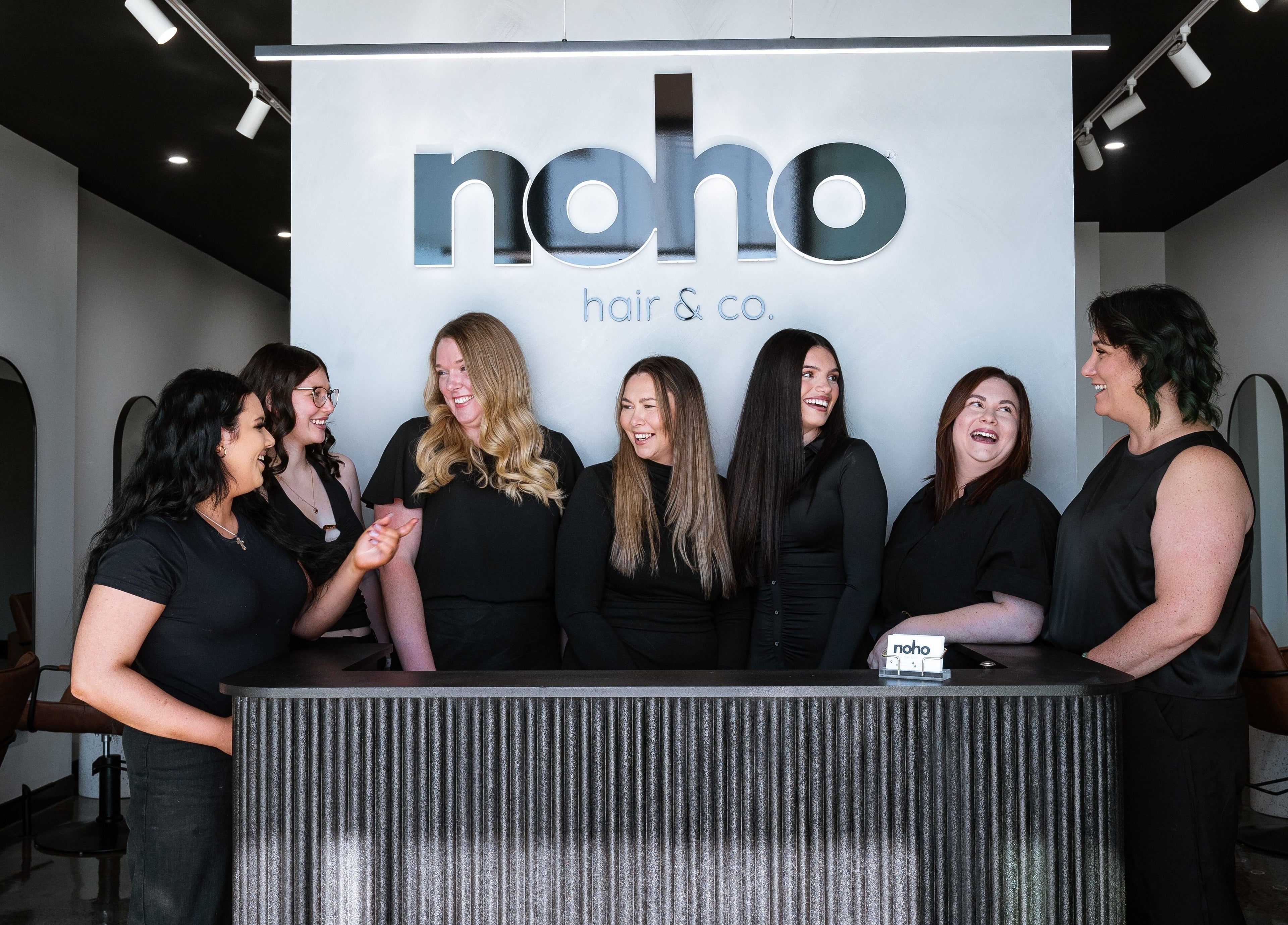 Team of stylists smiling at reception of Noho Hair & Co., Ormeau, Queensland, AU.