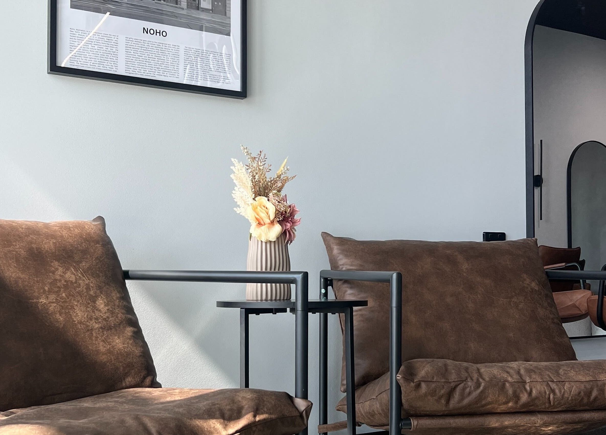 Cozy lounge area at Noho Hair & Co., Ormeau, Queensland, AU, featuring modern chairs and floral decor.