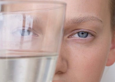 Close-up of a face behind a glass at By Adriane Roman, London, England, GB highlighting serene wellness.