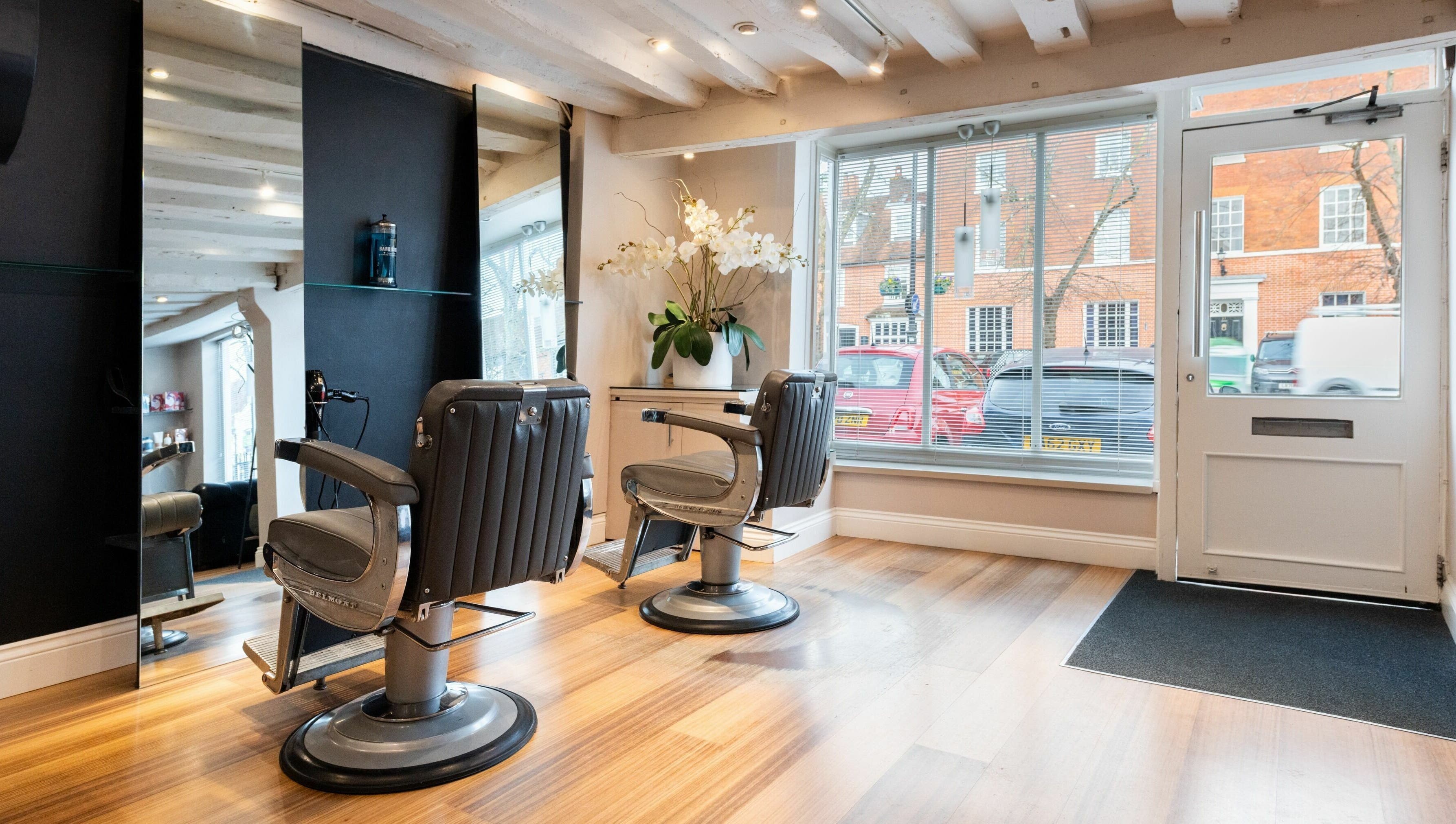 Chic interior of Albemarle Haircutters in Beaconsfield, England, GB with modern chairs and a large window.