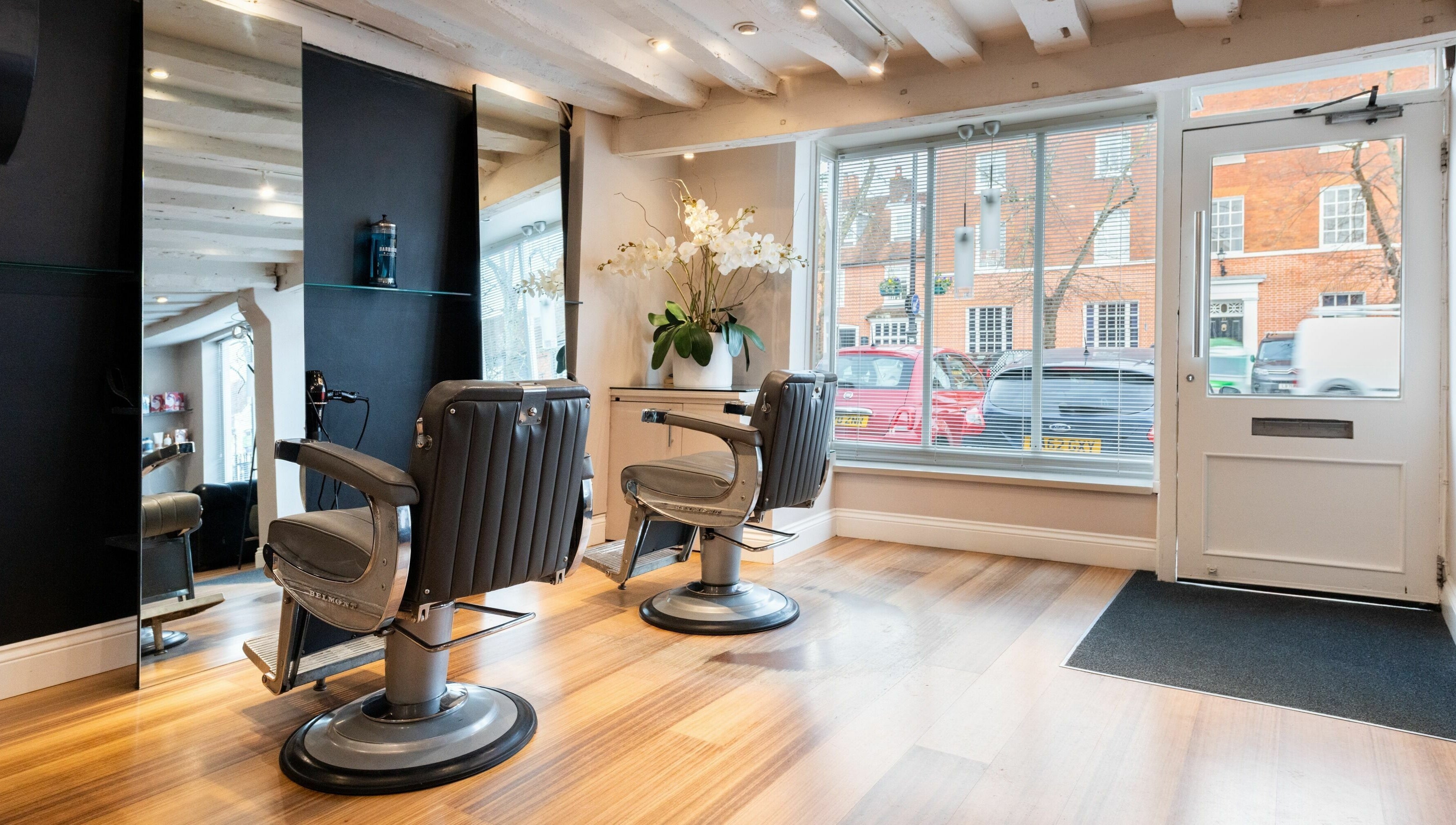 Chic interior of Albemarle Haircutters in Beaconsfield, England, GB with modern chairs and a large window.