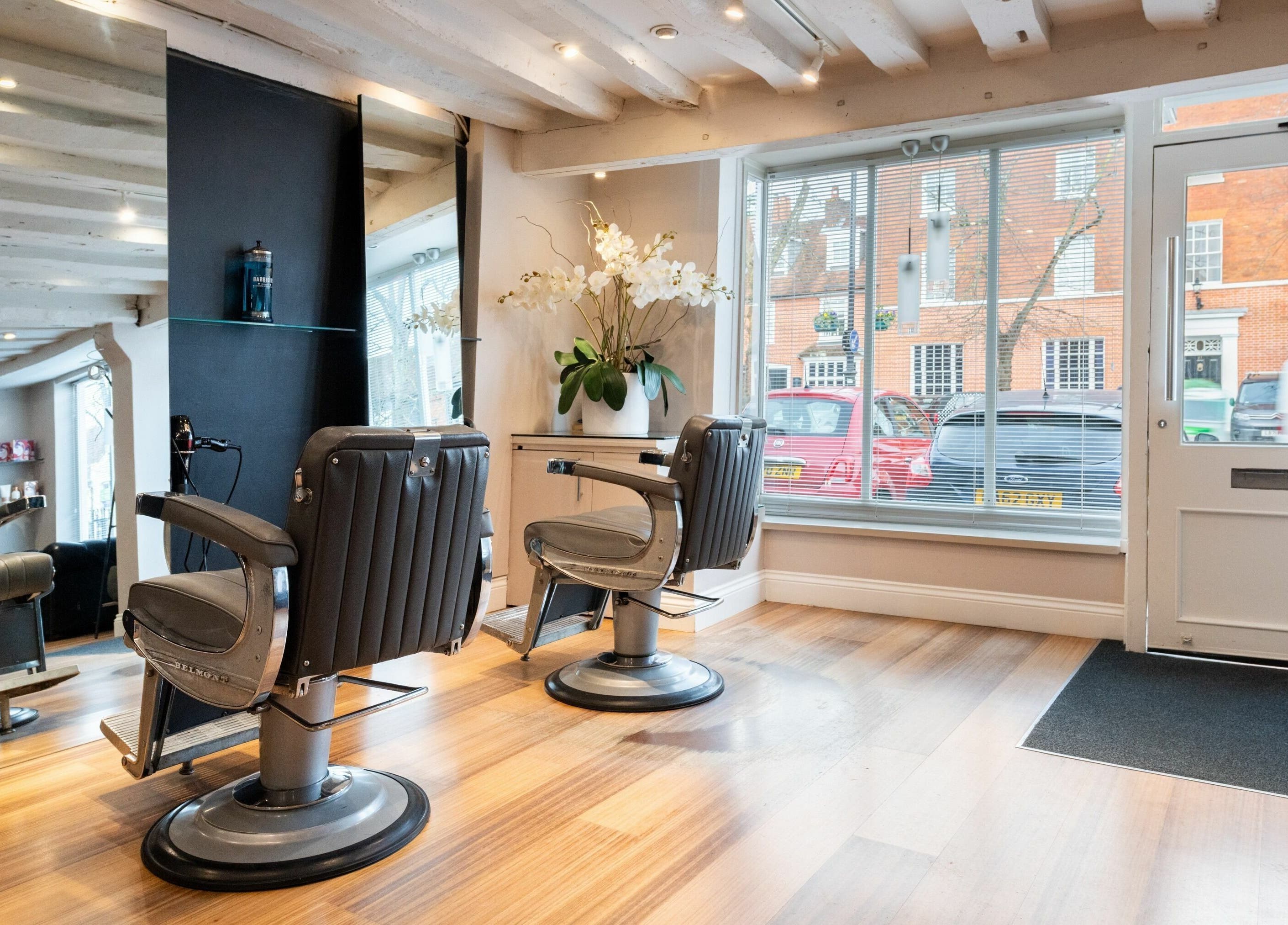 Chic interior of Albemarle Haircutters in Beaconsfield, England, GB with modern chairs and a large window.