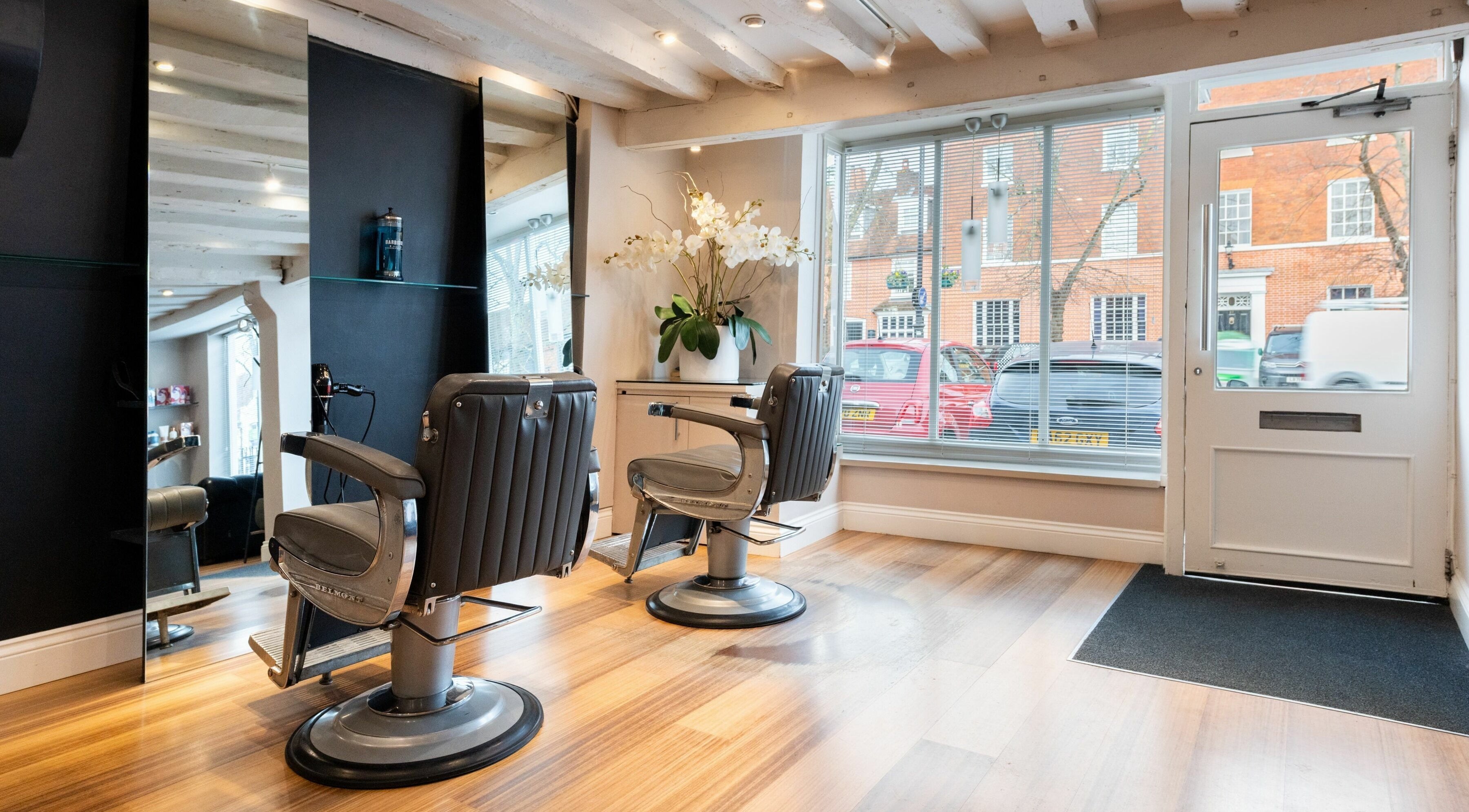 Chic interior of Albemarle Haircutters in Beaconsfield, England, GB with modern chairs and a large window.