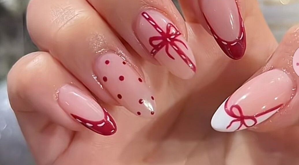 Thiết kế móng tay nghệ thuật tại M Cherie Nails, Hornchurch, England, GB với họa tiết nơ và chấm đỏ.