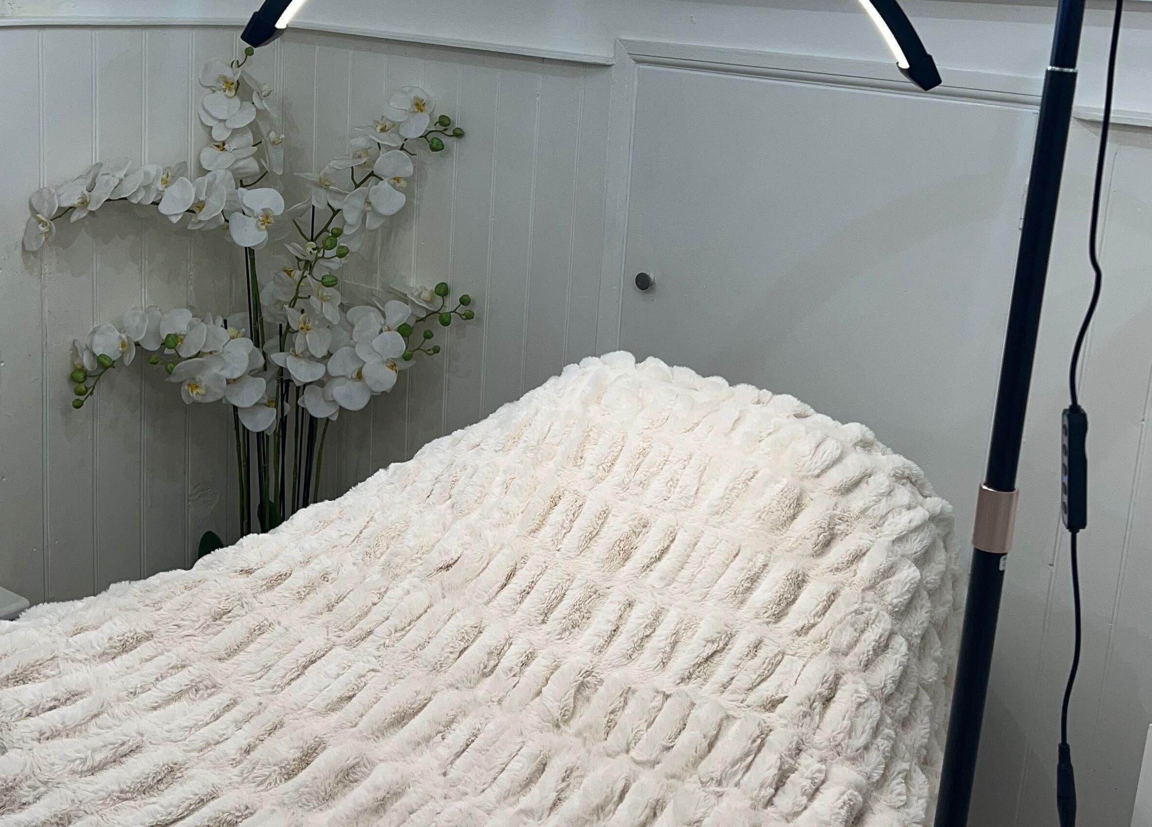 Cozy treatment bed at Lashes by Em, Harrogate, England, GB with elegant floral decor.