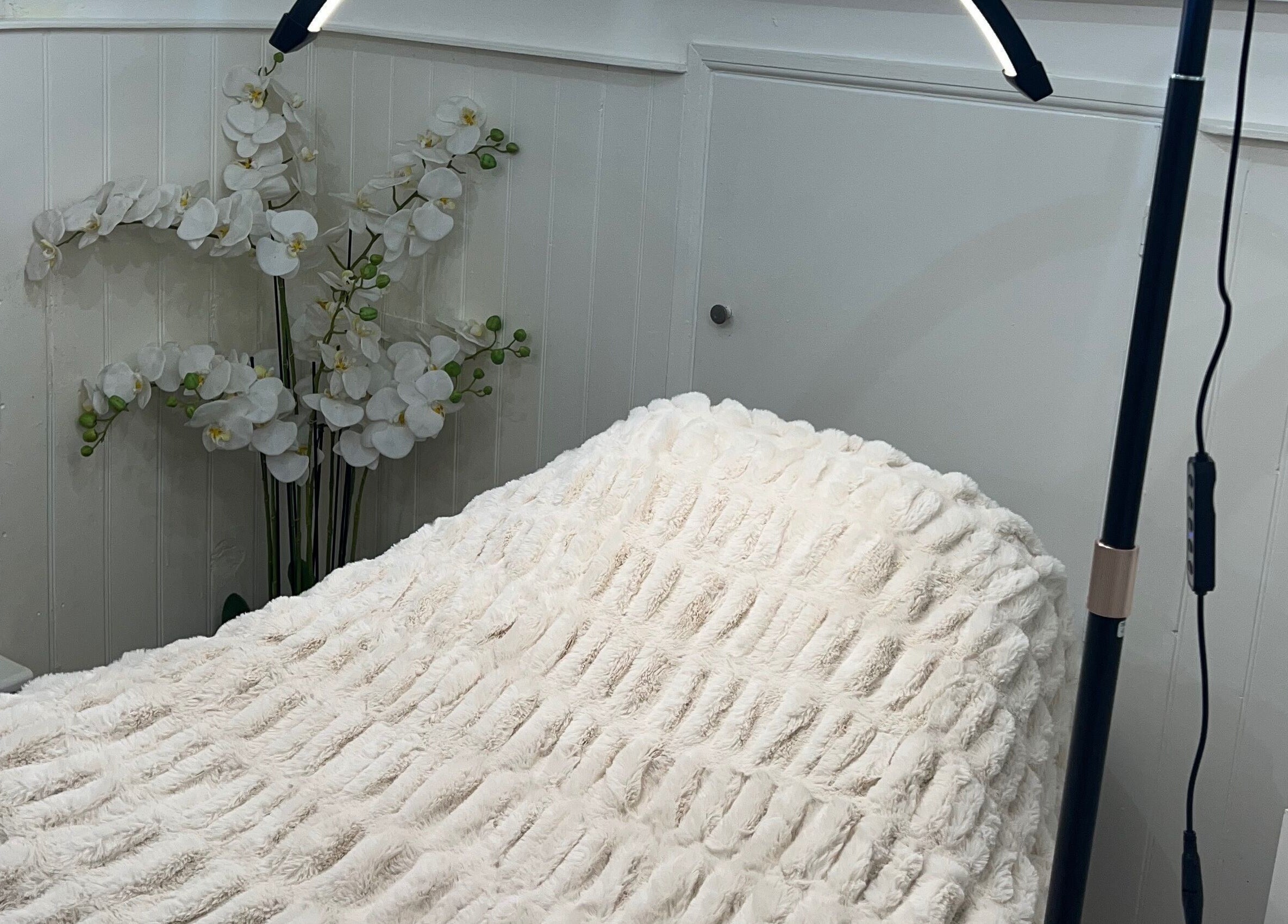 Cozy treatment bed at Lashes by Em, Harrogate, England, GB with elegant floral decor.