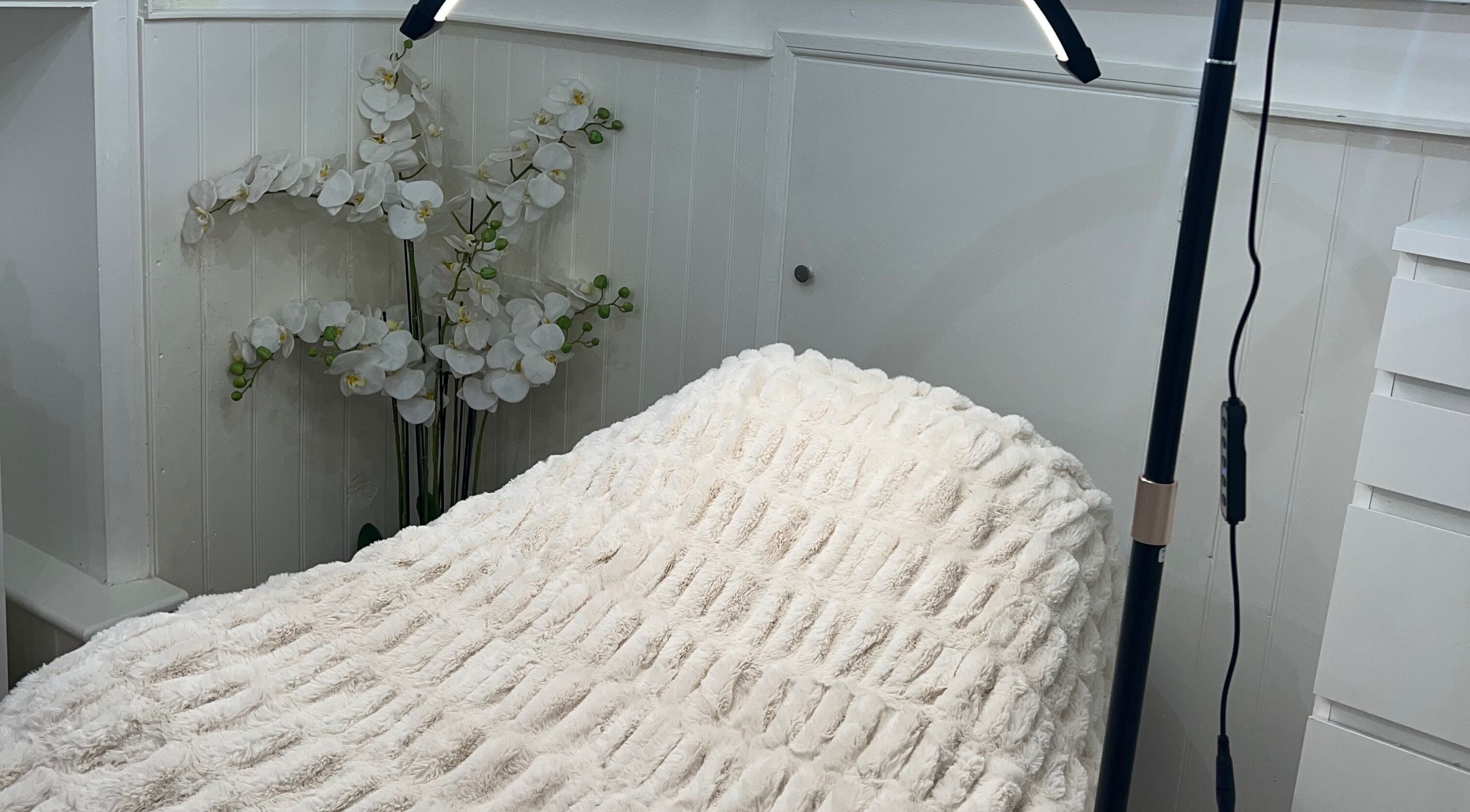 Cozy treatment bed at Lashes by Em, Harrogate, England, GB with elegant floral decor.