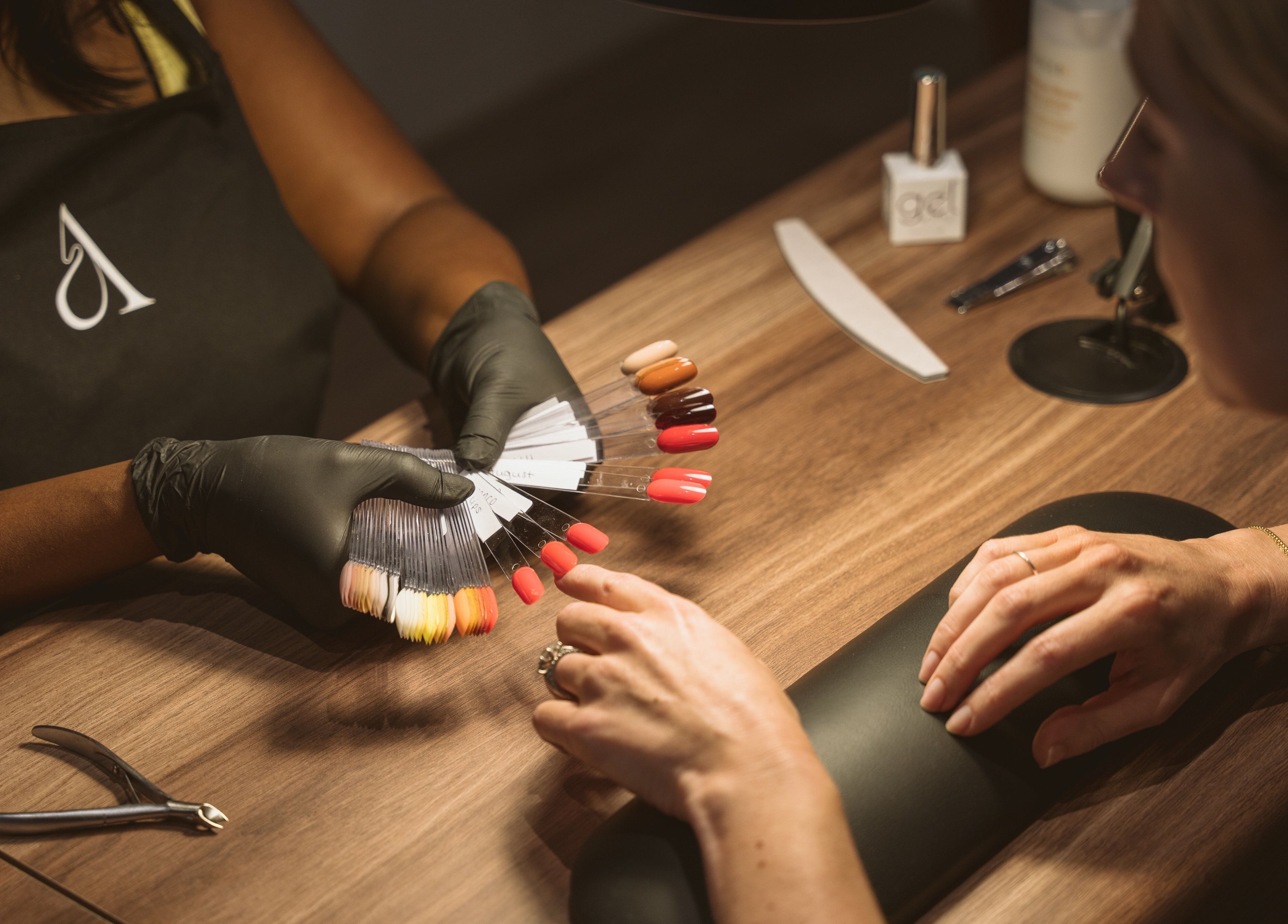 Client selecting nail polish at Awe London Canary Wharf, London, England, GB. A serene, upscale nail salon.