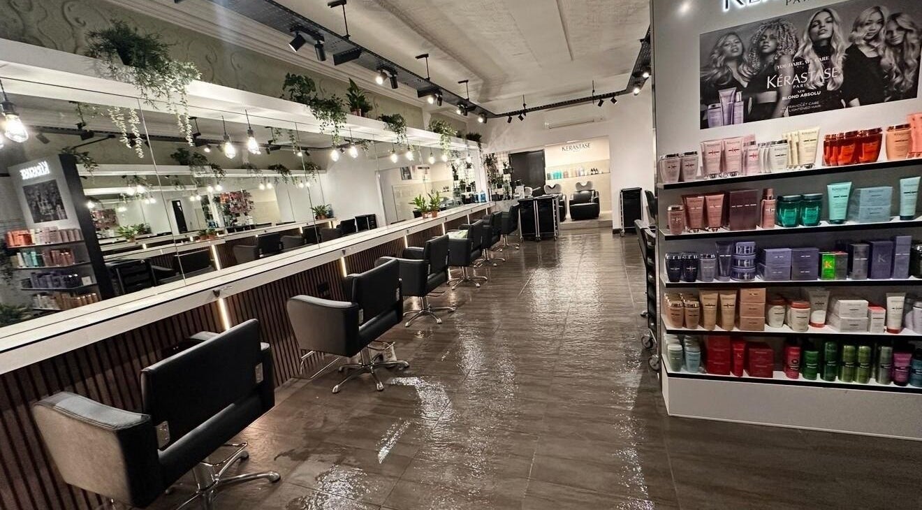 Modern salon interior at James Fulton Hair, Newcastle upon Tyne, England, GB, featuring styling chairs and product display.
