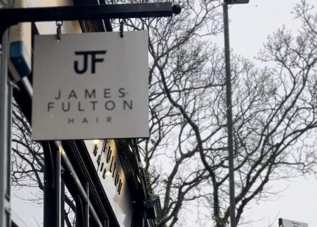 Sign for James Fulton Hair in Newcastle upon Tyne, England, GB, with trees in the background.