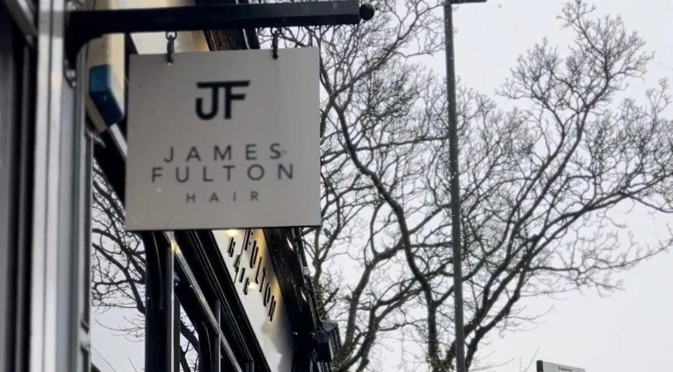Sign for James Fulton Hair in Newcastle upon Tyne, England, GB, with trees in the background.