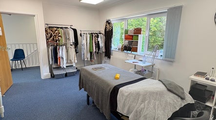 Relaxing treatment room at AmBhar Aesthetics, Hockley Heath, England, GB with massage bed and clothing rack.