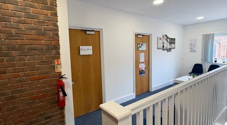 Interior hallway at AmBhar Aesthetics in Hockley Heath, England, showcasing entry doors and seating area.
