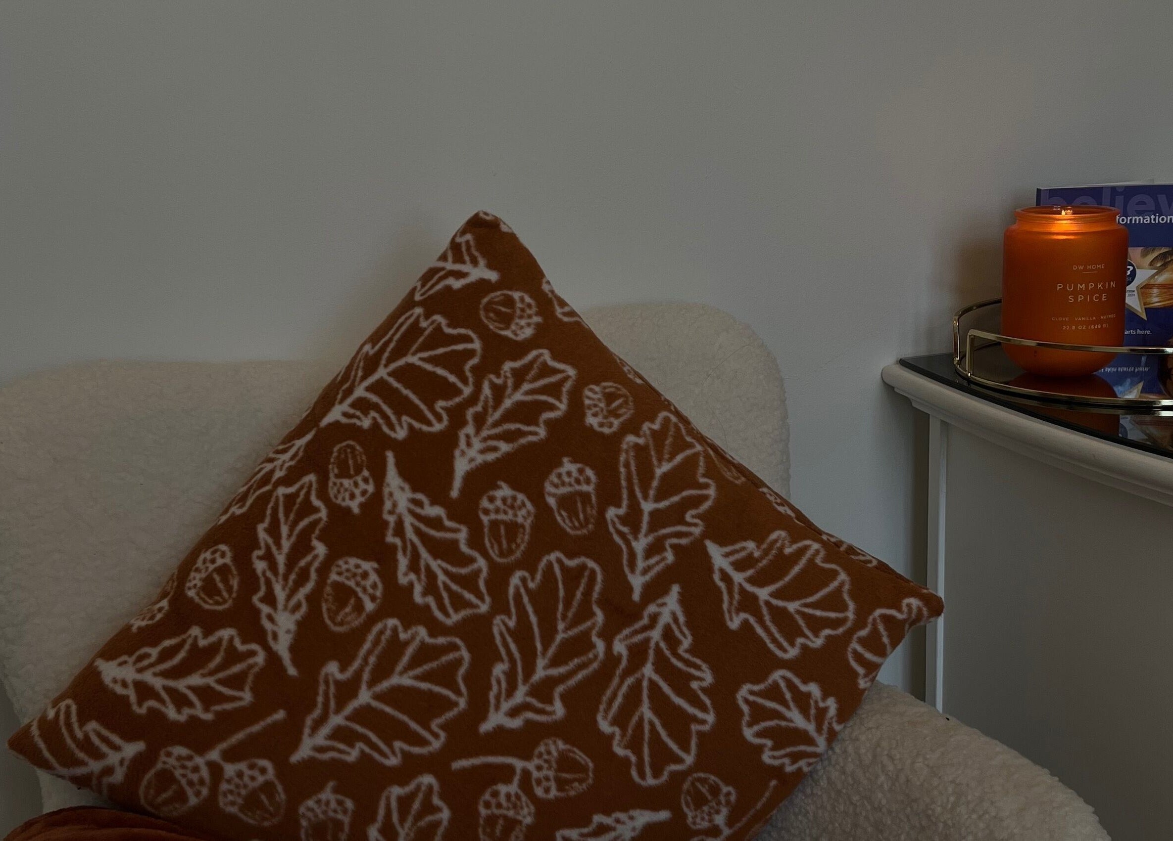 A cozy chair with a leaf-patterned cushion and a lit candle at The Essence Of Beauty, Chatburn, England.