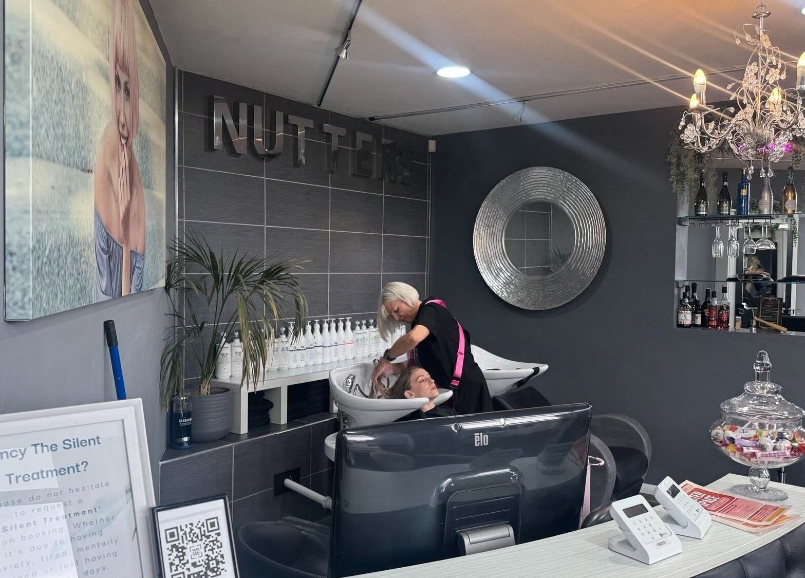 Hair stylist at Nutters, Exeter, England, GB, attends customer in a chic, modern salon setting.